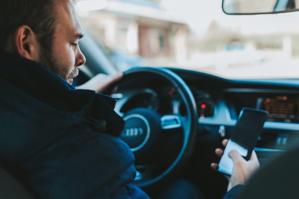 Person in the driver's seat of a car looking at their cell phone