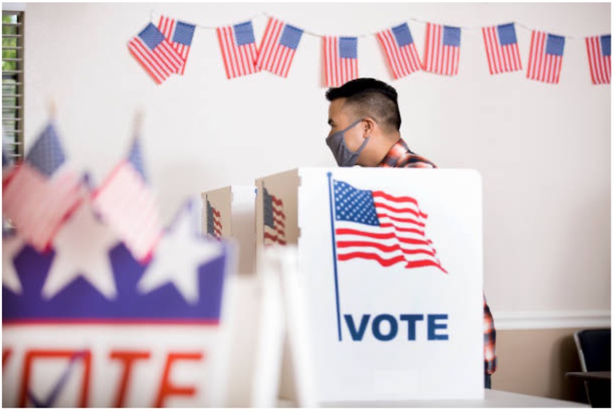 Image of a person voting at a voting booth.