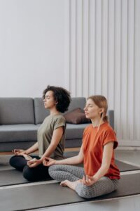 Two female students seated with their legs crossed in meditation.