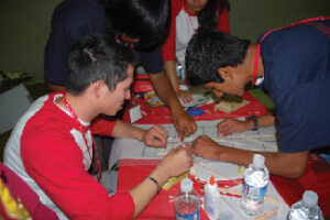 Four people gathered around a table attempting to figure out a problem together.