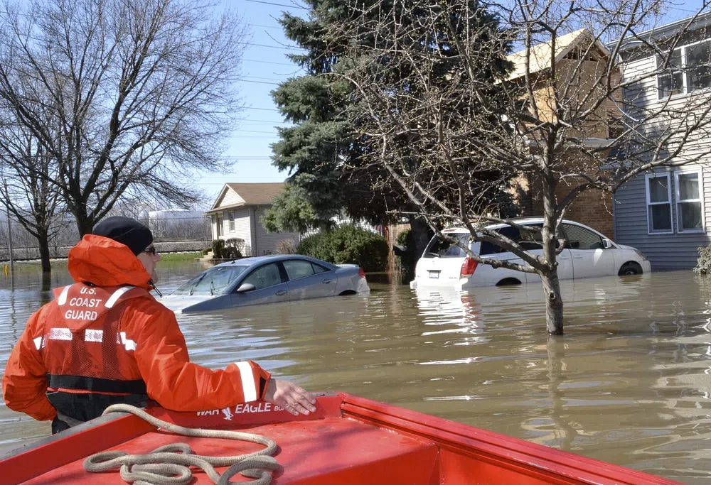 A member of the Coast Guard wades through deep water after a flood.