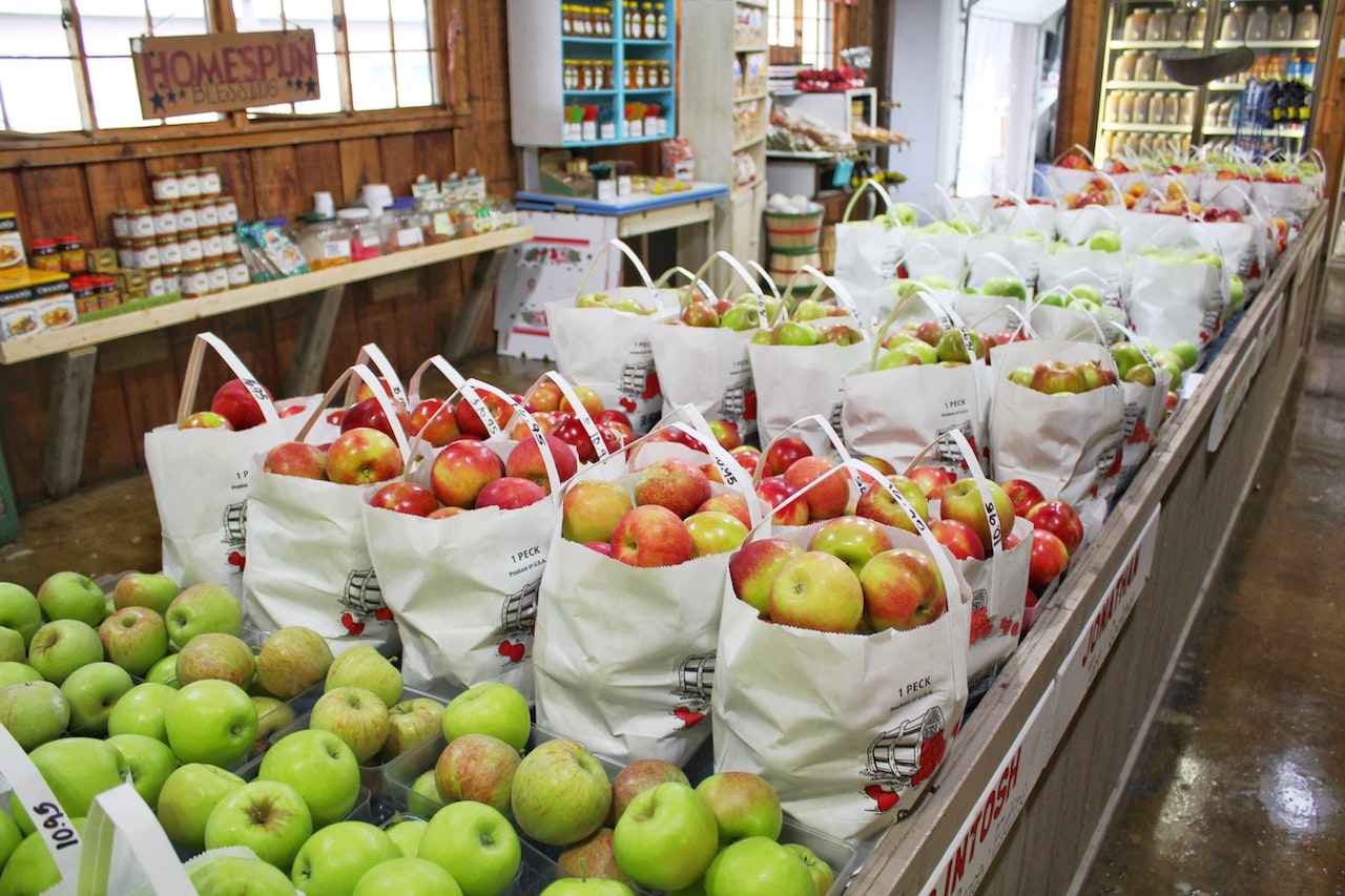 Interior of a grocery store with a display of several types of bagged apples.