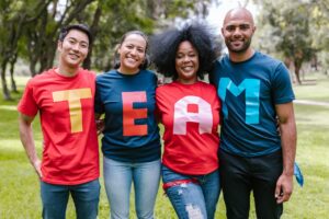 four people standing in a row wearing t shirts that spell T E A M