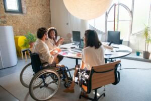 office meeting with two workers sitting in chairs and one in a wheelchair around a table