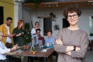 manager stands in foreground while her team works independently in the background of the office