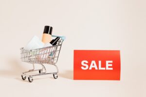 a miniature shopping cart filled with bottles next to a sign that says sale