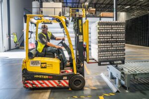 person driving a forklift moving a pallet of goods