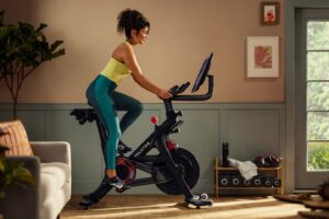 woman exercising on a Peloton bike in her living room