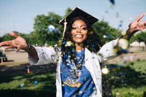 woman in graduation regalia throwing confetti