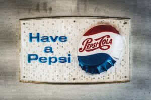 sign with a Pepsi Cola bottle cap that says, "Have a Pepsi"