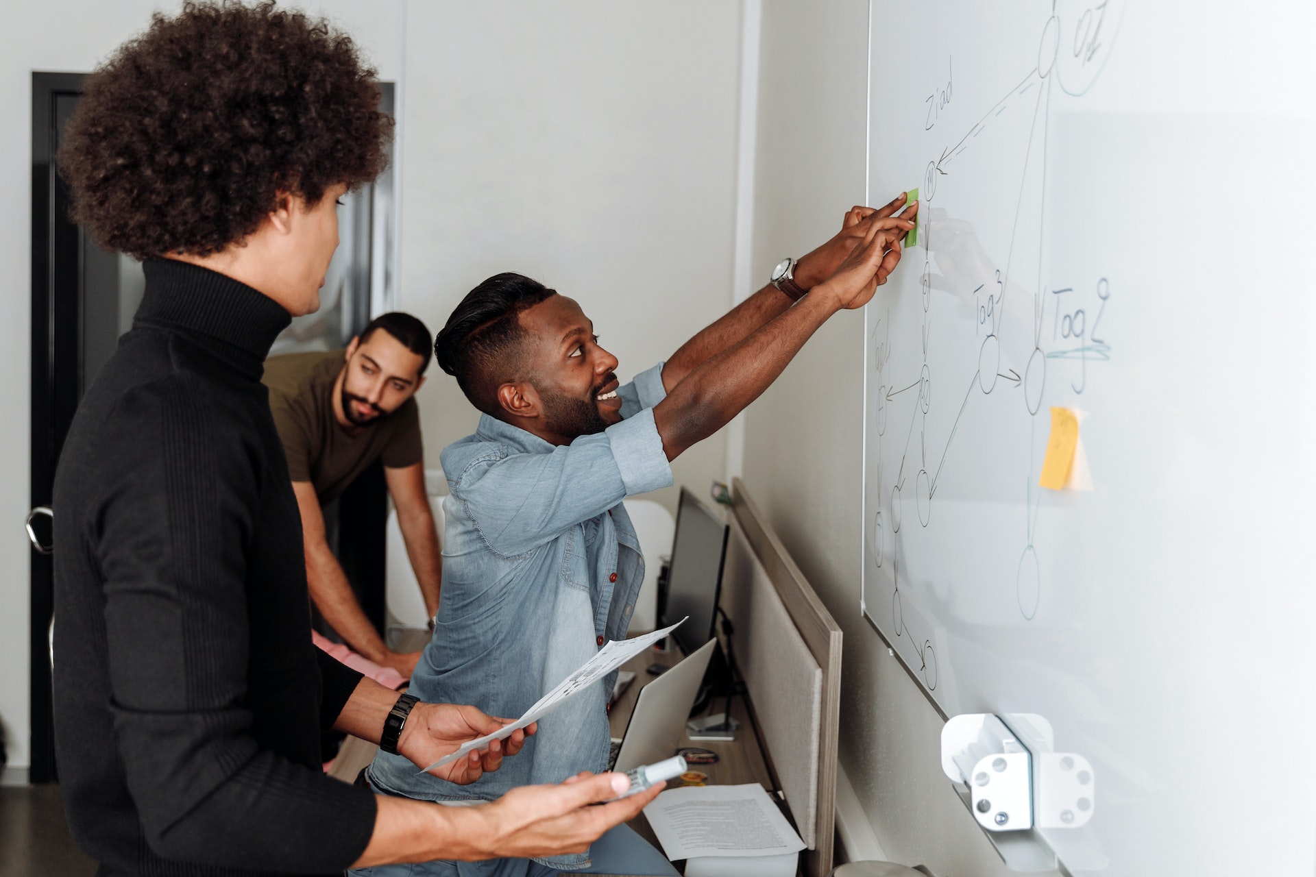 Colleagues talking and pointing to a whiteboard with drawings of figures