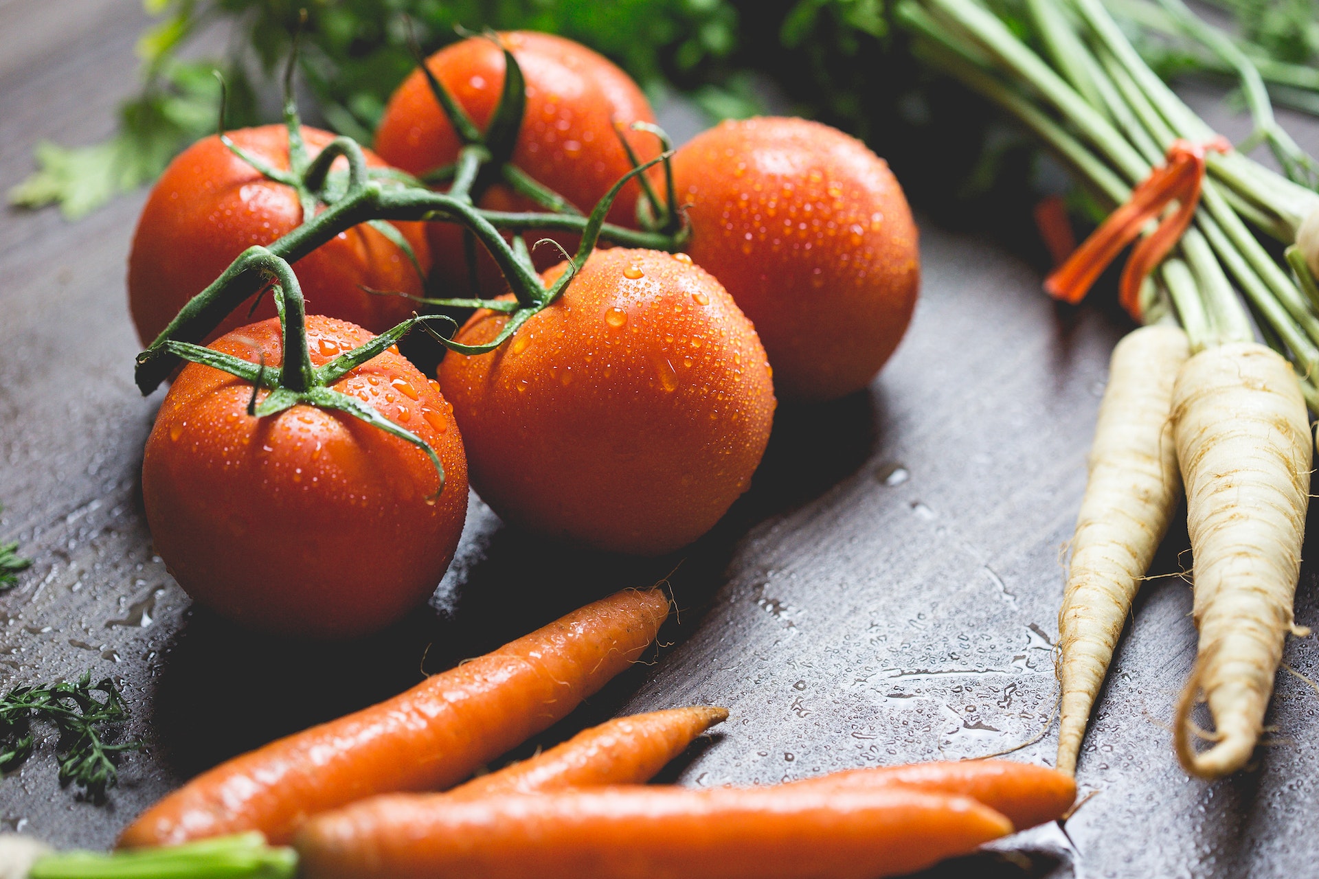 Freshly washed vegetables on a cutting board (tomatoes, carrots, and parsnips)