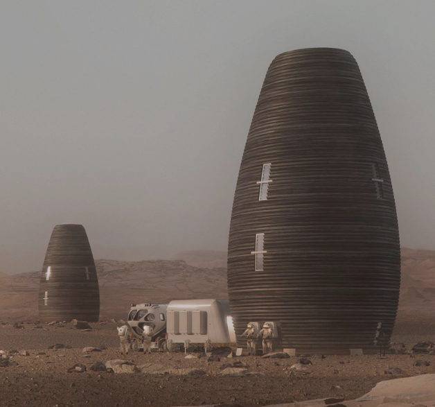 This image depicts a Mars colony scene with two tall, conical, ribbed structures resembling modern habitats. In the foreground, astronauts in spacesuits are interacting with a small white rover and a modular living unit. The landscape is barren and rocky, characteristic of the Martian surface, with a hazy sky in the background.