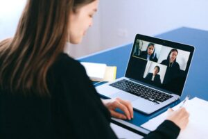 person sitting at a laptop on a video conference call with three other people