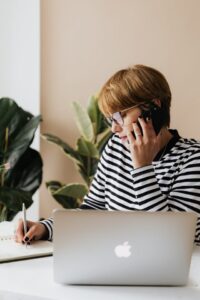 person on a phone call and taking notes
