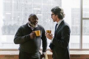 Two people each holding a mug having a conversation in an office.