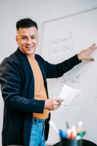 Professor teaching in front of a whiteboard explaining equations