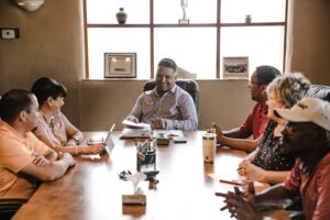A diverse team sits around a conference table at a meeting