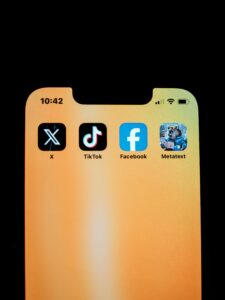 smartphone displaying icons for social media platforms X, TikTok, Facebook, and Metatext