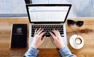 Person typing on a laptop with a spreadsheet on the screen